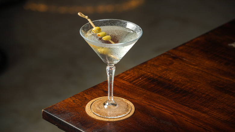 A dirty martini with olives on a table