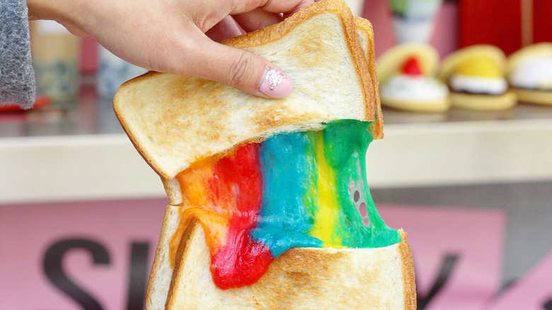 Rainbow toastie held in hand to show cheese pull