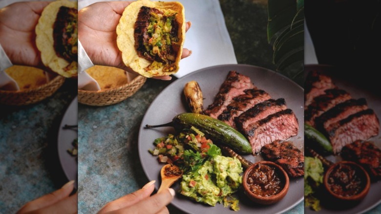 Plate of carne asada with guacamole, nopales, and salsa being spooned into a tortilla