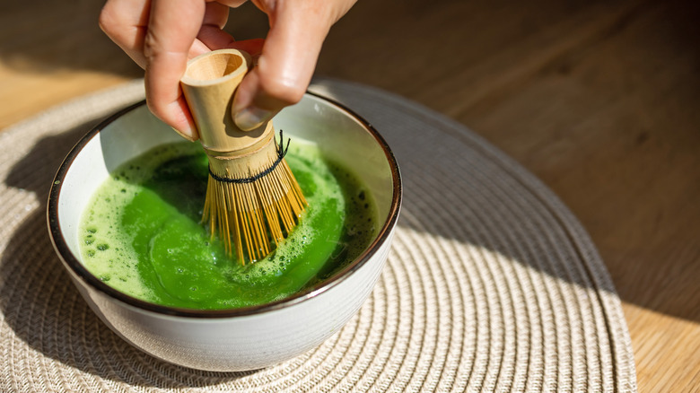 hand using bamboo whisk for matcha