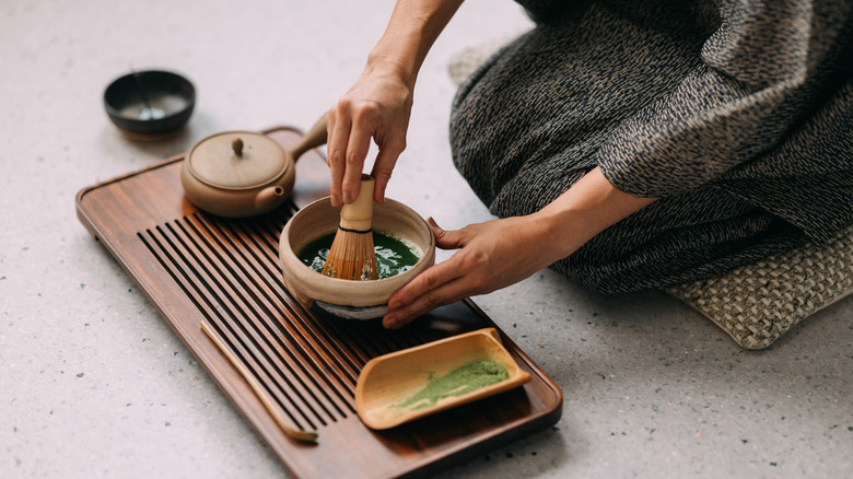 A person whisking a bowl of matcha tea with a chasen