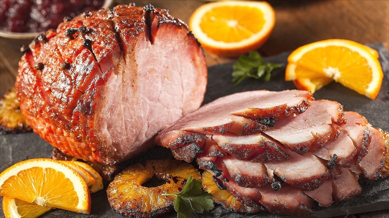 Sliced roasted ham with grilled pineapple rings and fresh citrus slices