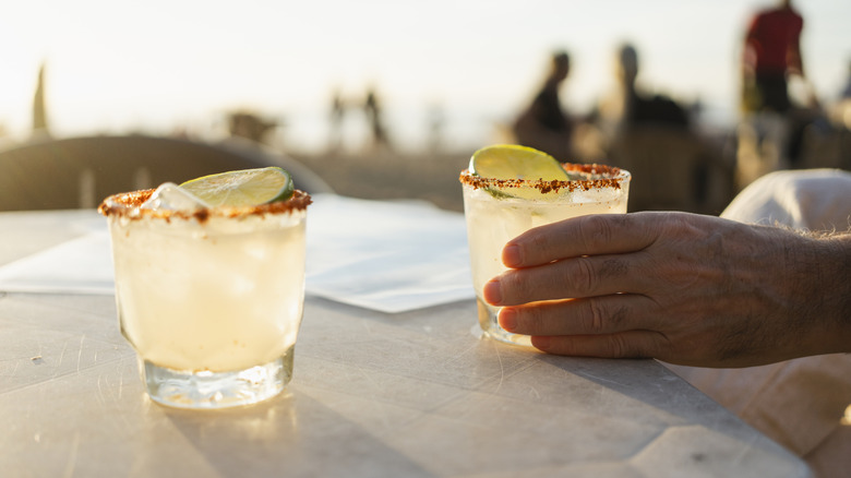 hand holding a margarita on an outdoor table
