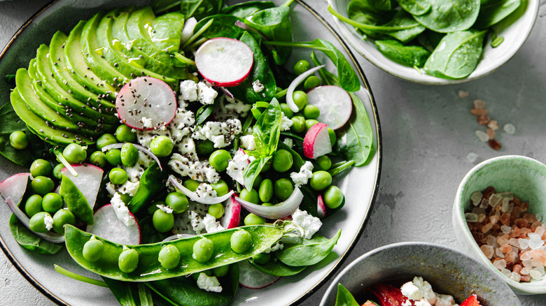 A bright green salad with avocado and snap peas.