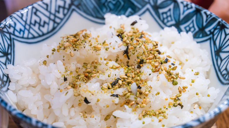 A bowl of white rice topped with furikake for umami flavor.