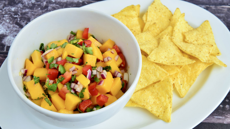 mango salsa in a bowl plated with tortilla chips