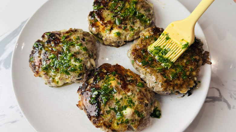 Brushing herb oil onto burgers