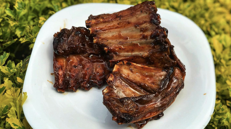 Grilled goat ribs on a white plate