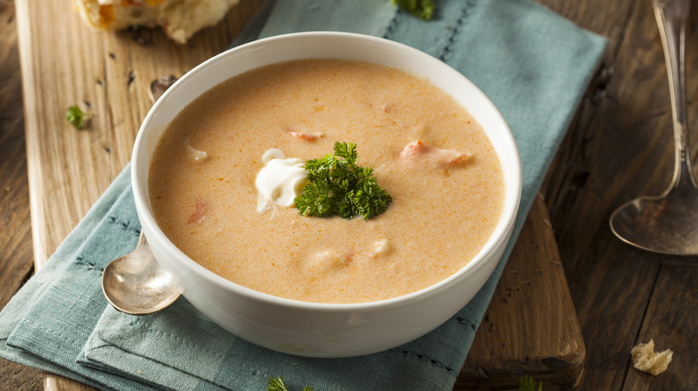 A bowl of rich and creamy lobster bisque on a table with a spoon and napkin