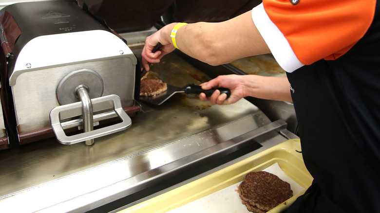 A McDonald's employee prepares a beef patty for a burger