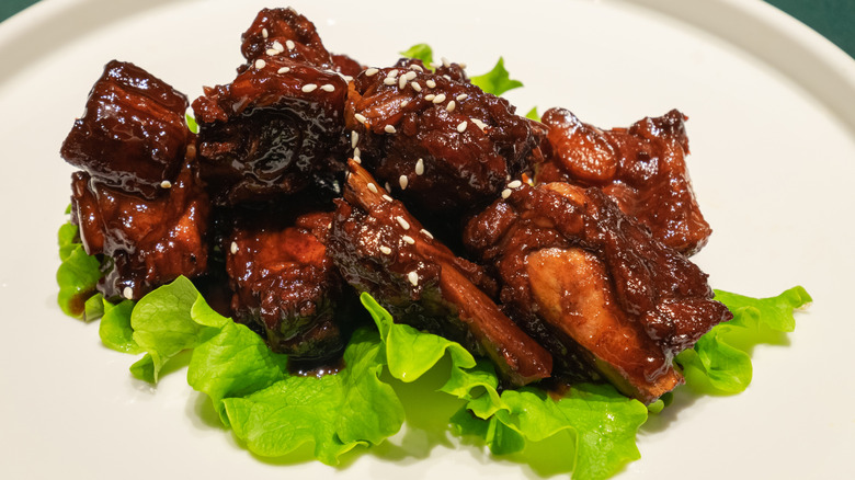 Chinese-style rib tips sit on a bed of lettuce on a white plate