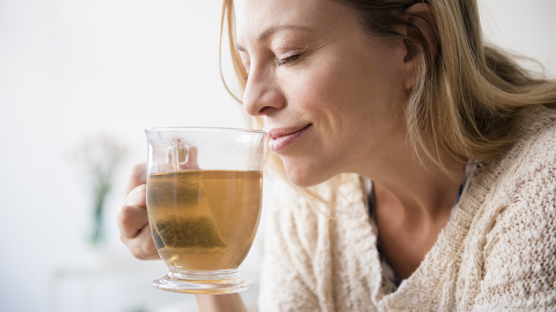 A woman savoring the scent of brewed tea with a tea bag in the cup