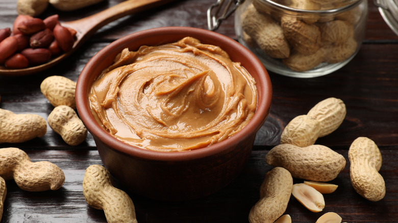 Tasty peanut butter in a bowl on a wooden surface.
