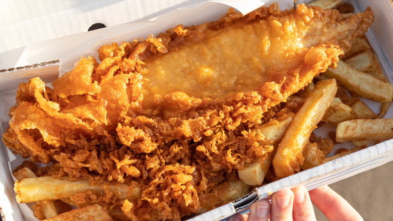 An order of traditional fish and chips served in a to-go box