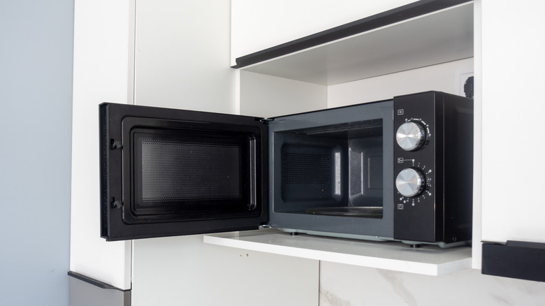 A microwave's door is open to display the emptiness inside.