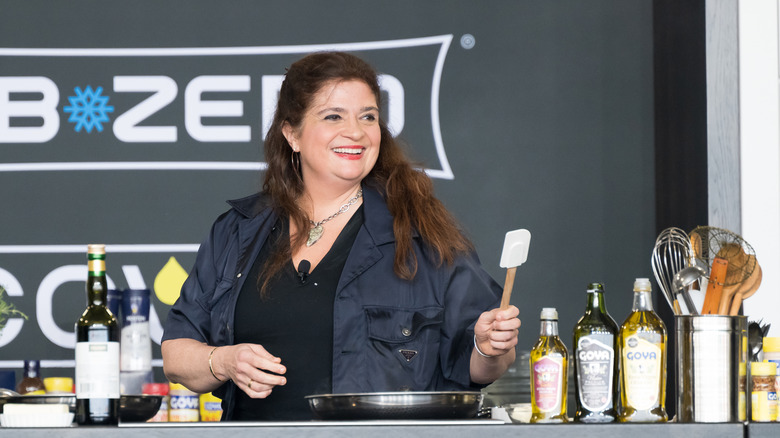 Alex Guarnaschelli holding a spatula and smiling