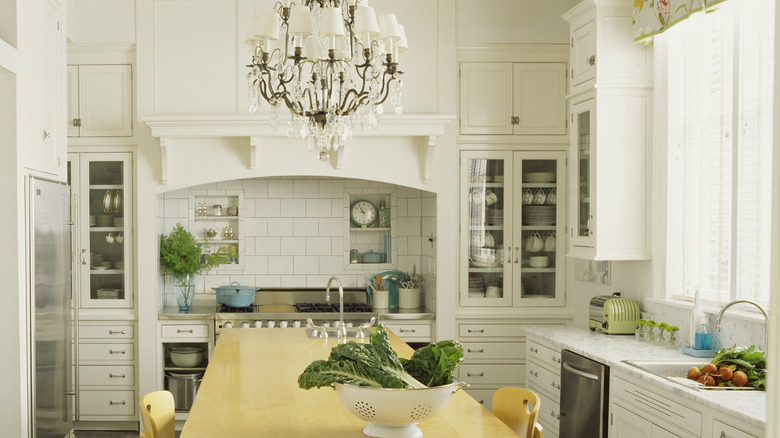 A white kitchen with a wooden dining table and a chandelier in the middle