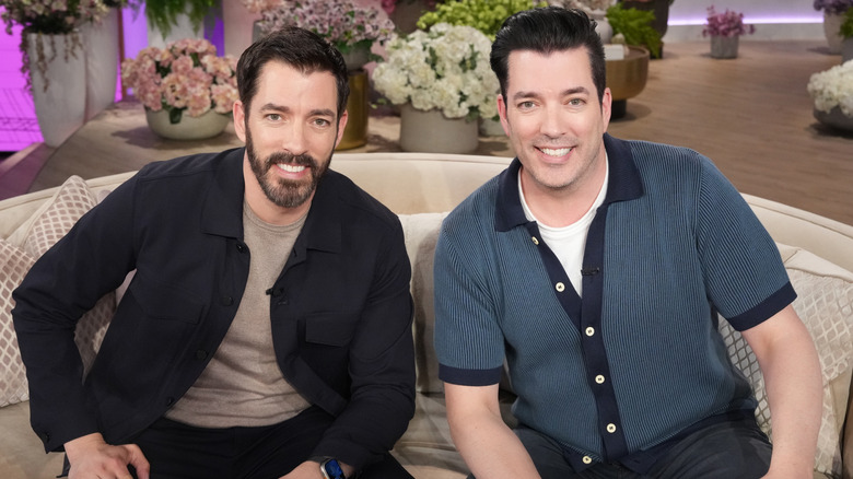 The Property Brothers smiling on a couch