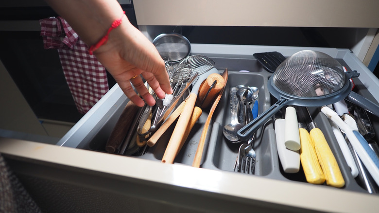 Handing reaching into a drawer of kitchen utensils