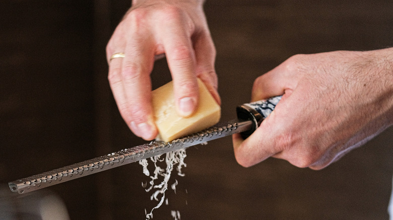 Using a Microplane to grate a hard cheese into fine strips
