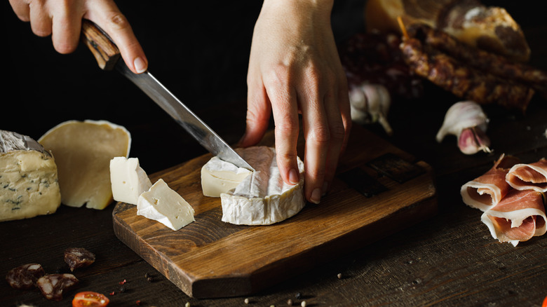 Person cutting a camembert block.