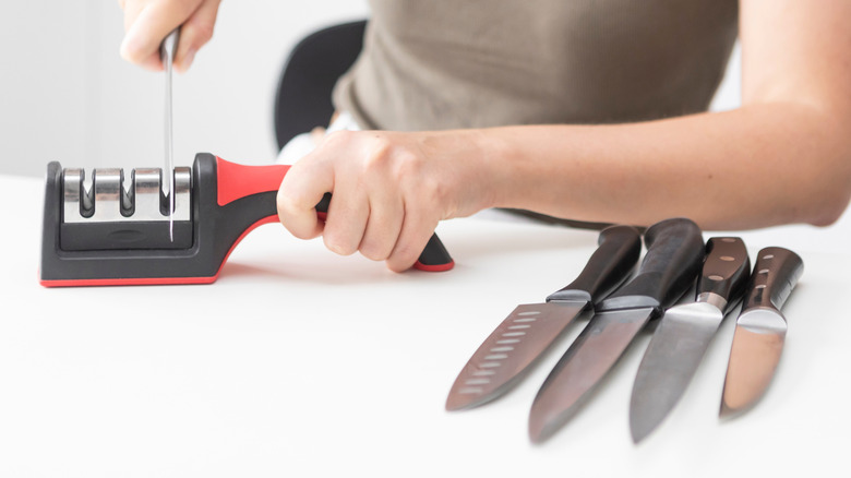 Woman using manual knife sharpener.