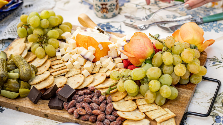 Charcuterie board spread with crackers, cheese, fruit, and chocolate