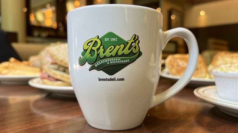 a Brent's Deli mug on a table with food