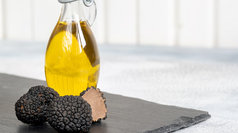 3 truffles at the base of a bottle of oil.