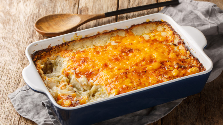 A hearty casserole set on a wooden table, with melty, gooey cheese that makes it look more inviting