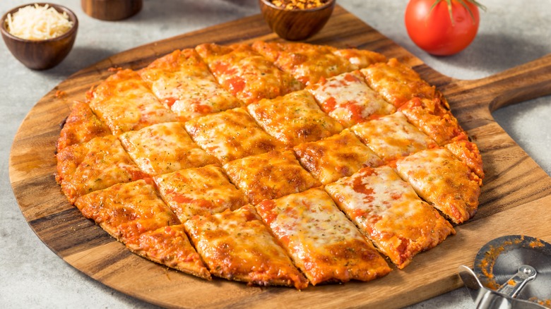 A sliced tavern-style pizza on a wooden board