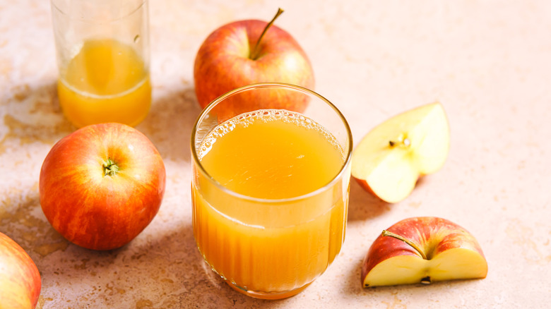 Glass of fresh apple juice and whole apples.