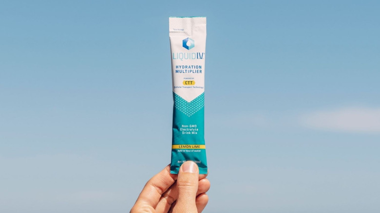 Hand holding packet of Liquid IV in front of a blue sky