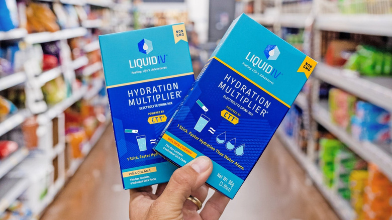 Hand holding Liquid I.V. boxes in a store aisle