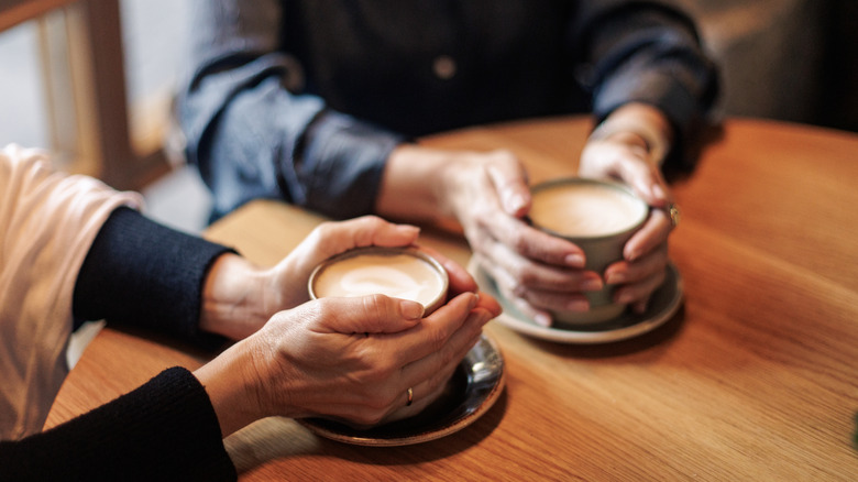 Two people holding cups of coffee