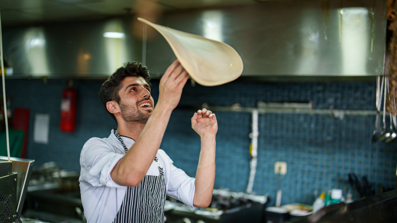 A chef tossing pizza dough in the air.