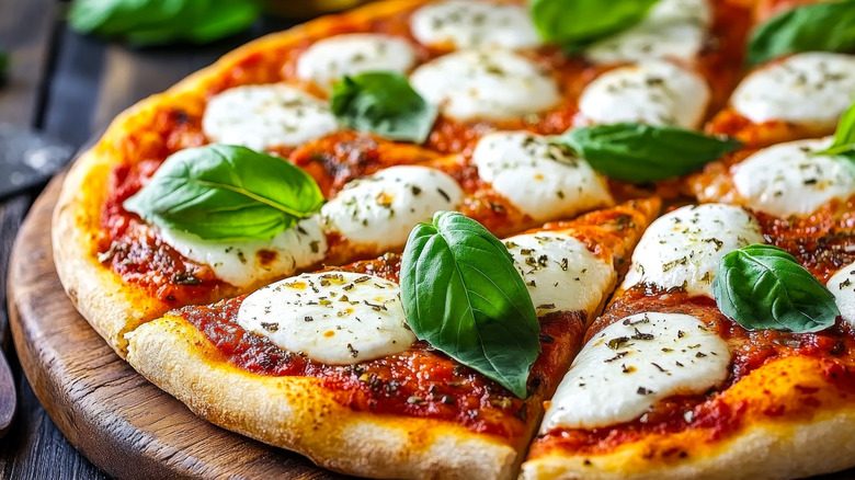A closeup of a sliced pizza topped with fresh mozzarella and basil.