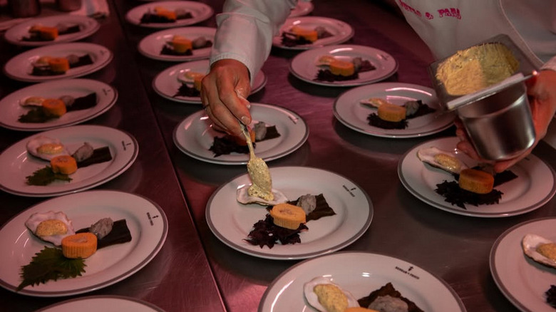 A chef at bompass and parr plating several dishes of oysters