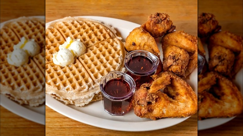 a plate of Roscoe's fried chicken and waffles with maple syrup