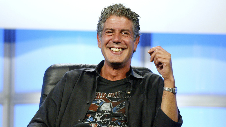 Celebrity chef Anthony Bourdain smiling on stage at an event.