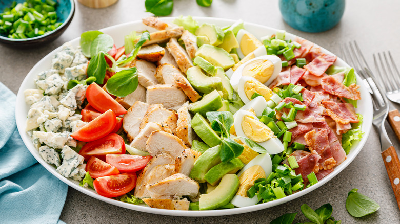 A large Cobb salad on a white plate in lovely natural light.