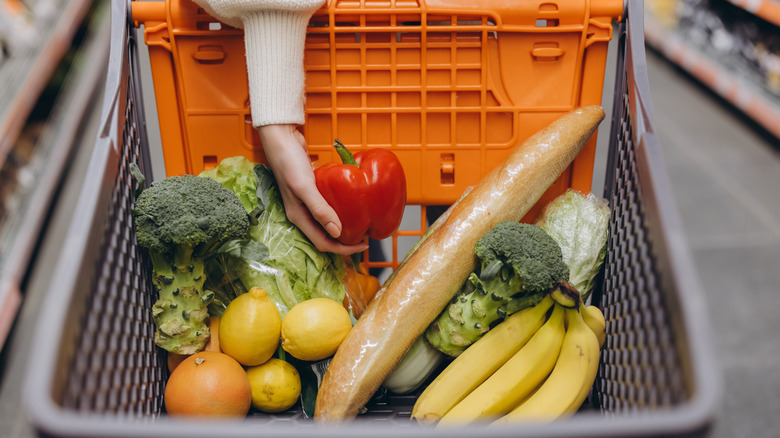 hand holding groceries inside a shopping cart in the store