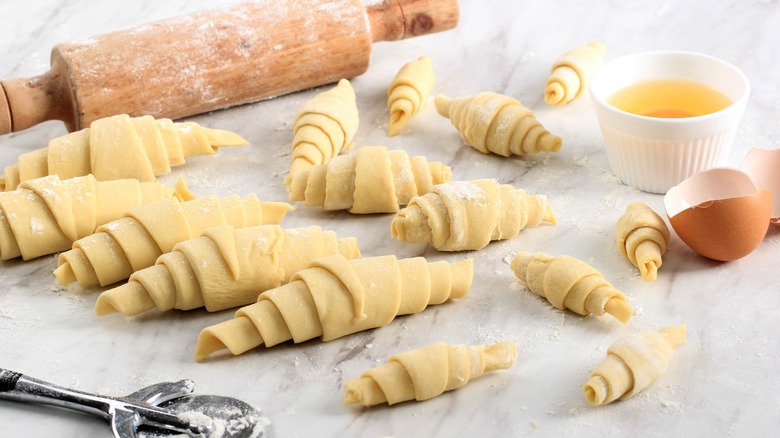 Rolled croissants sitting on a marble counter ready to be baked.
