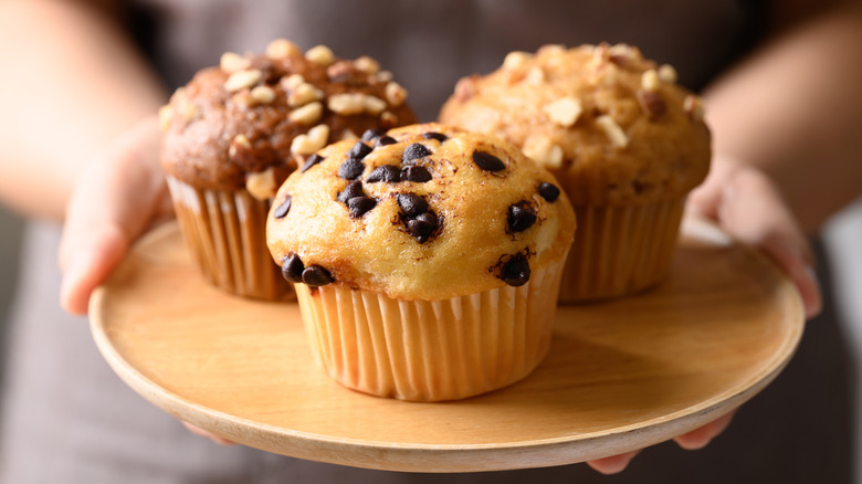 Three different muffins on a wooden plate