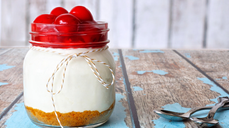 Cherry cheesecake in a Mason jar on a picnic table