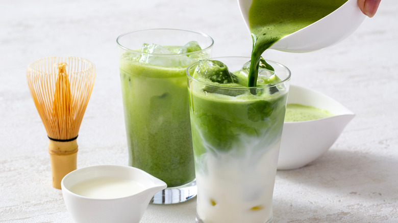 Person adding matcha to a glass of iced matcha latte