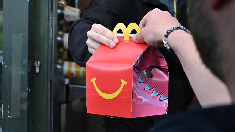 Person grabbing a happy meal box from drive-thru window.