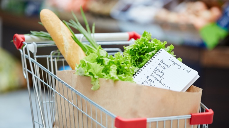 Shopping cart with bread, vegetables, and a shopping list