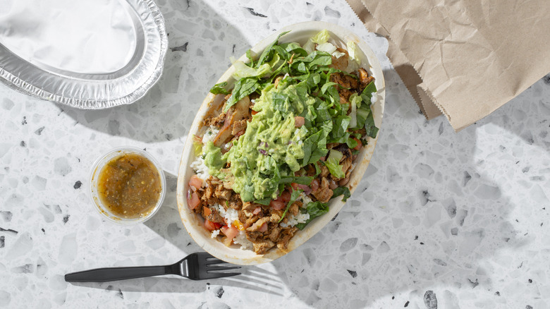 A top-down view of a Chipotle burrito bowl with fork and salsa
