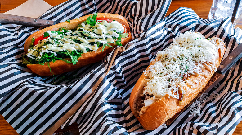 hot dogs topped with veggies and cheese